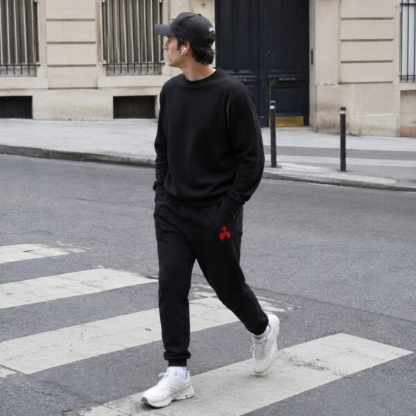 Gros plan sur la broderie chrétienne Caritas d'un pantalon de survêtement homme